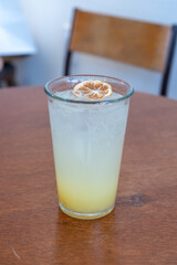 A glass of iced lemonade soda with lemon on the table in the cafe