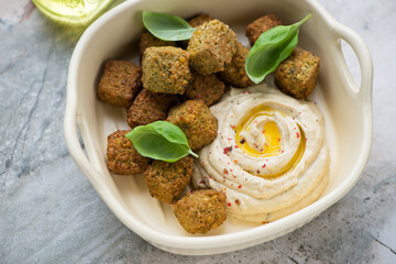 Beige serving tray with falafel and hummus, horizontal shot on a grey granite background, middle close-up