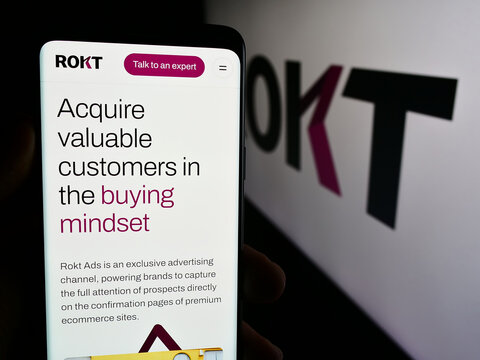 Stuttgart, Germany - 07-14-2024: Person holding mobile phone with web page of e-commerce technology company Rokt Pte. Ltd. in front of logo. Focus on center of phone display.