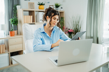 One young beautiful caucasian business woman working in office on laptop and looking through charts