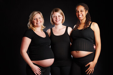 Pregnant, friends or women in studio with portrait, bonding or group together for stomach or support. Family, diversity or happy pregnancy care for gestation, maternity or gynecology black background