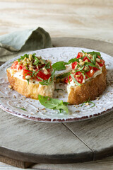plate of bruschetta with soft cheese, concasse tomatoes and basil on the table