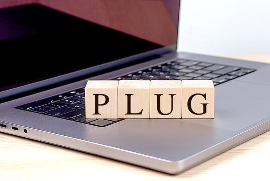 PLUG word on wooden block on a laptop , business concept