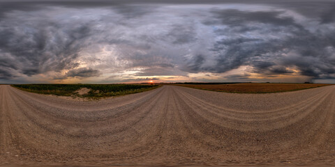 hdri 360 panorama on gravel road among fields in nasty evening before sunset with dark clouds in...
