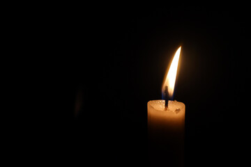 Illuminate the darkness with a flickering candle, casting a warm glow against a dark backdrop,...