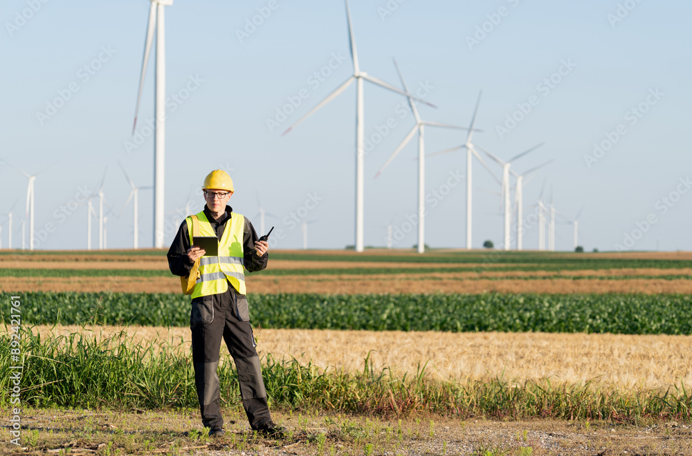 Poster Engineer with digital tablet controls wind turbines