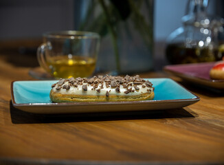 A chocolate covered pastry sits on a blue plate on a wooden table