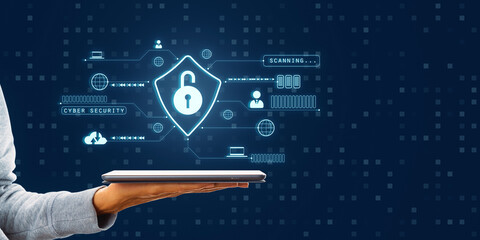 Hand holding a digital tablet with cybersecurity hologram on blue background.