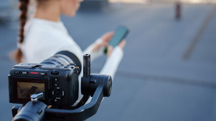 Camera on stabilizer films how a sporty girl uses a smartphone with a green screen