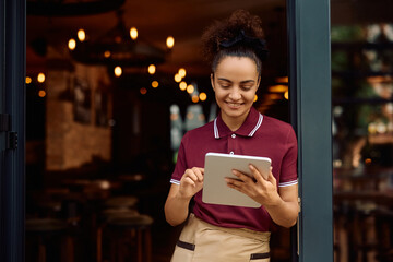 Happy waitress using digital tablet while working in a cafe.