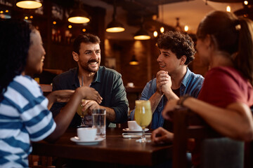 Happy man and his friends talking while enjoying in  café.