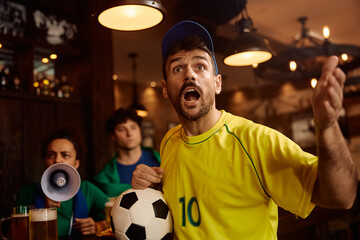 Passionate soccer fan watching  match on TV in pub.