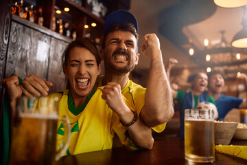 Passionate sports fans celebrating victory of their favorite team while watching  game in pub.