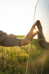 Close-up of a hand touching a solar panel at sunset © scharfsinn86