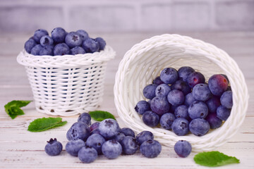 Blueberry berries in white baskets on a white wooden background.
