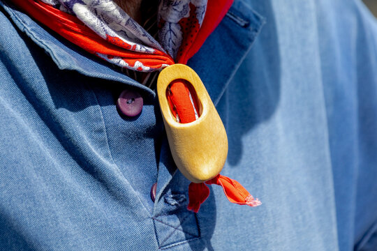 Selective focus of a men with blue polo wearing red scarf with wooden shoes woggle ring, Dutch man with traditional vintage costume in Edam, One of the famous cheese market, North Holland, Netherlands