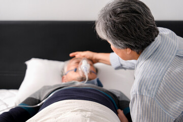 senior woman caring of dying husband who lying on bed,hand touching his head to support and...