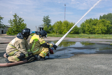 Firefighters hold the fire barrel when water is supplied under high pressure. The fire barrel...