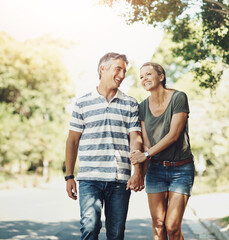 Obraz premium Happy, holding hands and couple in park walking for bonding, relationship and love outdoors. Nature, marriage and man and woman laugh in street for romance, affection and relax on weekend together