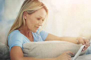 Mature, woman and tablet with relax on sofa for internet browsing, social media app or online subscription. Person, smile and digital technology on couch in living room for reading ebook or blog post