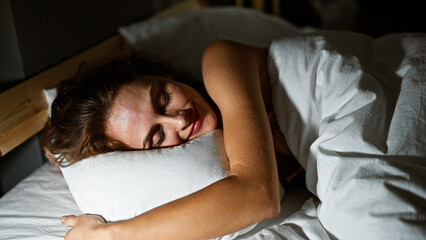 A peaceful young woman sleeping comfortably in a cozy bedroom, illuminated by warm light.