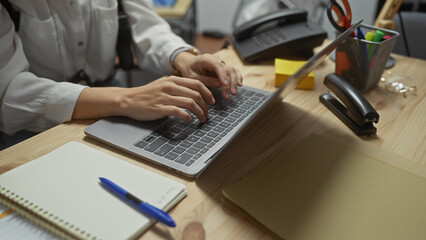 Caucasian woman working at a police department office with a laptop on a case.