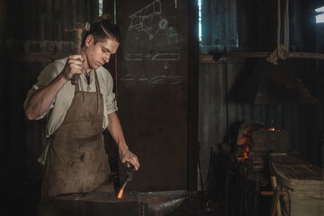 Blacksmith forges a red-hot metal piece on an anvil in a rural forge. Traditional crafts