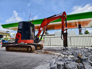 Excavator using hydraulic hammer for breaking concrete at a construction site