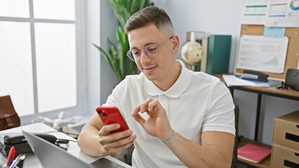 Handsome hispanic man in glasses using a smartphone in a modern office setting