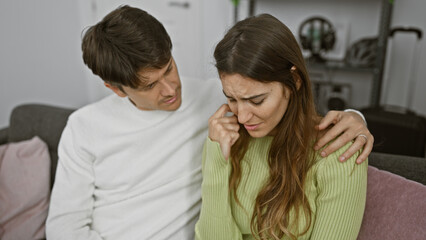 A concerned man comforting a sad woman in a cozy living room, portraying support, relationship, and indoor emotions.