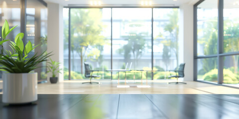 Blurred background with plant sits in the foreground on a dark wood tabletop, with a view of a bright office space with large windows