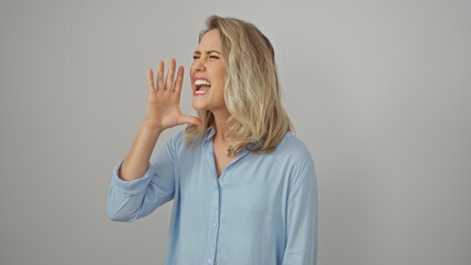 Blonde woman in blue shirt shouting against a white background, portraying emotion and...
