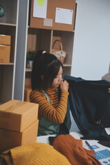 vlogger, blogger small SME business asian beautiful woman using mobile phone video call for sell clothes live stream selling online, show product present detail at home office, entrepreneur ecommerce
