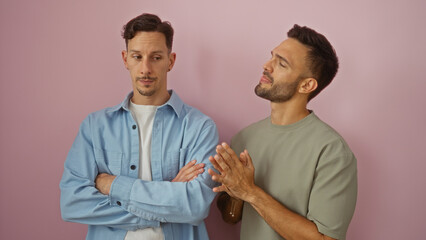 Obraz premium Two men standing together against a pink background, depicting a gay couple in a loving relationship with expressions suggesting conversation and companionship.