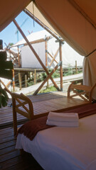 Cozy tent interior with wooden furniture and fresh towels set against african nature, providing a peaceful camping adventure setting.