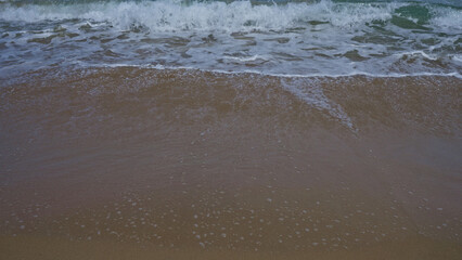 Waves gently wash over a sandy beach, capturing the serene essence of the ocean shoreline.