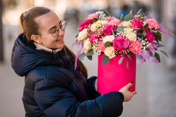 Smiling girl in a glasses holds a chic bouquet of pink and lilac roses and peonies in her hands