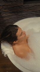 A serene woman relaxes in a bubbly bath at a luxurious hotel, embodying tranquility and self-care.