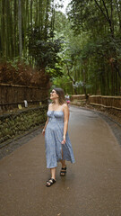 Beautiful hispanic woman with glasses, smiling confidently as she stands amongst kyoto's lush bamboo forest, looking around, full of joy and amazement.