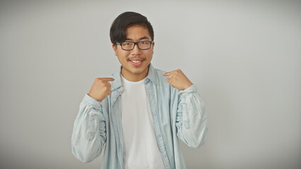 A confident young asian man in a denim shirt points to himself against a white background