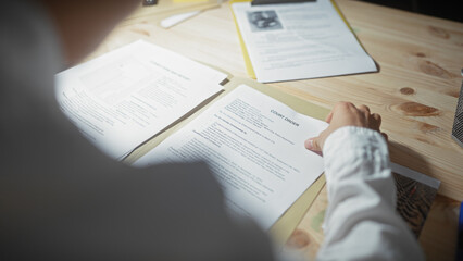 Asian man reviews legal documents in office setting, evoking a sense of detective crime...