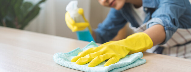 Cleanliness asian young woman working chore cleaning on table at home, hand wearing glove using rag...
