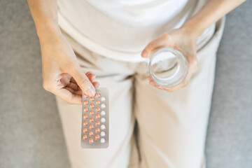 Contraception and pregnancy, menstruation concept, birth control pills asian young woman hand holding hormonal oral contraceptive medicine, take pharmaceutical to prevention, safe virus sex disease.