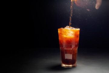 Close-up shot of pouring sparkling water with ice in a glass. placed on a black background