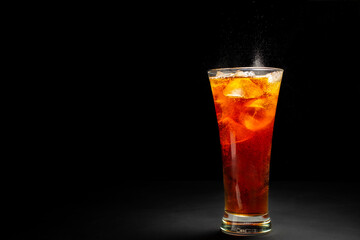 Black soft drink with ice in a glass Placed on a black and dark background.
