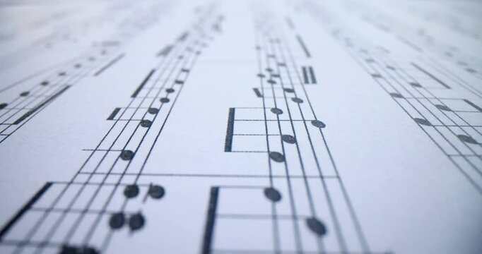 Music conceptual background macro view of white music notes with sheet music. Notes of musical work concept