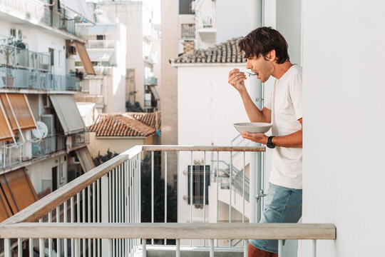 Young man eating cereal on the terrace of Athens apartment