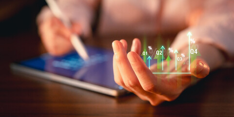 Close-up of a businessperson's hand using a stylus on a digital tablet, with holographic financial...
