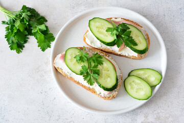 a plate of food with a sandwich on it and a slice of cucumber