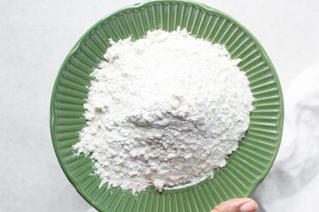 Overhead view of all purpose flour in a green plate, top view of baking flour in a plate